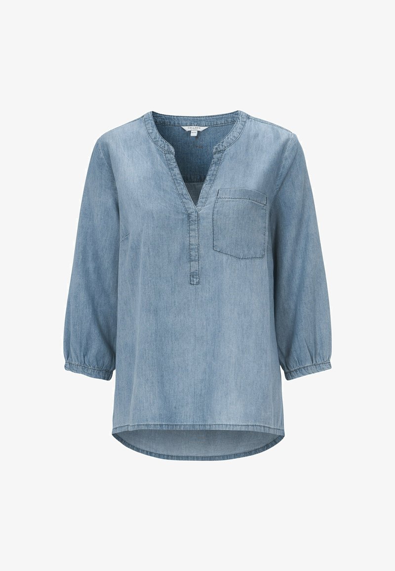Helle blaue Denimbluse mit halbem Knopfverschluss, langen Ärmeln mit elastischen Bündchen und einer Brusttasche. Der Saum ist abgerundet und hinten etwas länger.