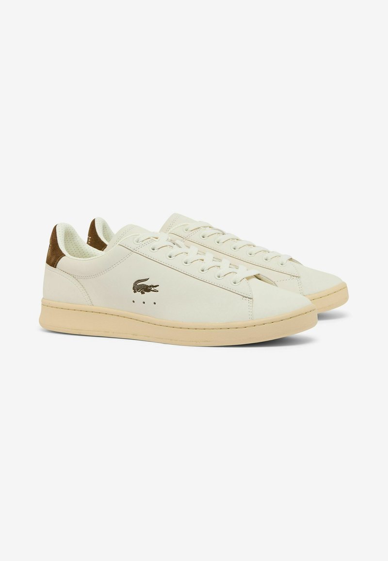 Coppia di sneaker in pelle avorio con suole beige, dettagli marroni sul tallone e piccolo logo coccodrillo sul lato.