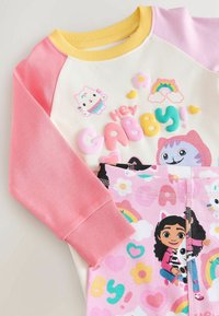 Baumwoll-Pyjama-Set mit einem cremfarbenen Oberteil und rosa Ärmeln, bedruckt mit bunten Charakteren, kombiniert mit rosa Hosen, die mit Mustern und Grafiken verziert sind.
