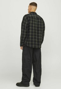 Groen en zwart geruite flanellen shirt met een rechte pasvorm, voorzien van knoopsluitingen en een rugplooitje, gecombineerd met zwarte cargobroek.