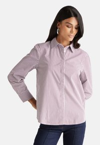 Camicia a righe bianca e rosso scuro, con colletto classico, maniche lunghe e una forma leggermente aderente.