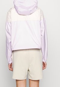 Paars lichtgewicht jack met een capuchon, kleurgebroken ontwerp, elastische manchetten en een casual fit, gecombineerd met beige shorts.