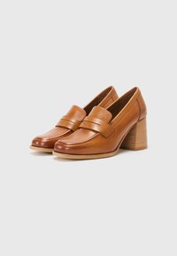 Brune lærloafers med rund tå, en bred rem over vampen og en medium blokkhæl. Glatt tekstur med sømdetaljer.