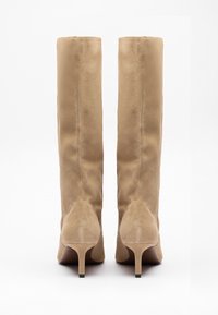 Beige suede knee-high boots with a fitted design, tapered pointed toe, and a slender high heel. Smooth texture, minimal hardware.