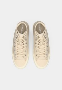 Baskets en toile beige avec œillets en métal, lacets bicolores, semelles en caoutchouc et bout arrondi. Avec le logo "CONVERSE" sur les semelles intérieures.