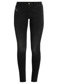 Pantalones vaqueros negros ajustados de denim con una textura suave. Presentan un diseño clásico de cinco bolsillos y detalles de costura a lo largo de los lados.