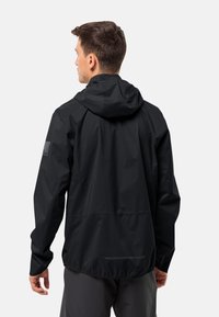 Giacca impermeabile nera con cappuccio, fondo elastico con coulisse e tasche laterali. Presenta un logo del marchio discreto sulla manica. Tessuto leggero.