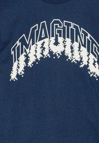 Mørkeblå t-shirt med ordet "IMAGINE" i store, pixeliserede hvide bogstaver, med en gradienteffekt mod bunden. Blødt, glat stof.