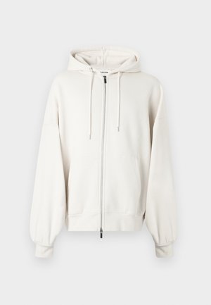 Sweat à capuche blanc avec fermeture éclair, coupe décontractée. Doté d'une capuche avec cordon de serrage, de deux poches avant, ainsi que de poignets et d'un ourlet côtelés. Texture douce.