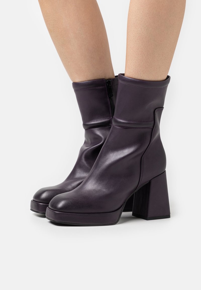 Bottes cuir violettes pour enfants avec une texture lisse, talons blocs, bouts arrondis, et un design montante doté d'une fermeture éclair latérale.