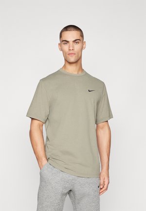 Heleoliiviroheline Nike t-särk lühikeste varrukatega, ümmargune dekoltee ja must logo rinnal, koos hallide dressipükstega.