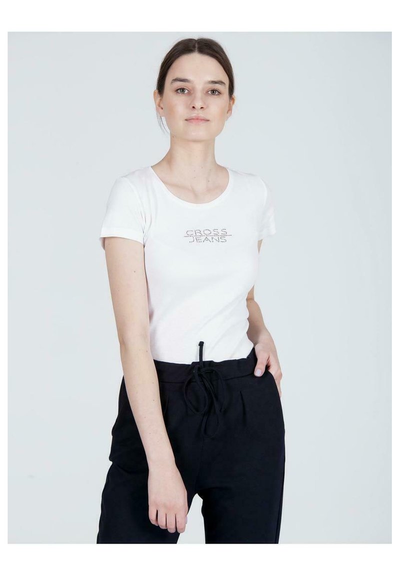 Biała koszulka z krótkim rękawem, okrągłym dekoltem i logiem "CROSS JEANS" wyłożonym kryształkami na piersi, zestawiona z czarnymi spodniami z troczkami.