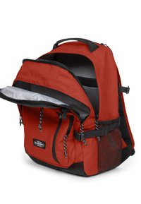 Mochila roja con interior gris, compartimento principal con cremallera, bolsillos frontales, bolsillo lateral de malla, detalles en negro y correas ajustables.