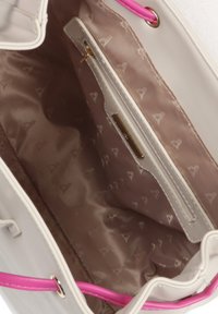 Wnętrze torebki w jasnym kolorze, wykonane z gładkiego, satynowego materiału z subtelnym wzorem serc. Posiada różowe uchwyty i złote detale zamka.