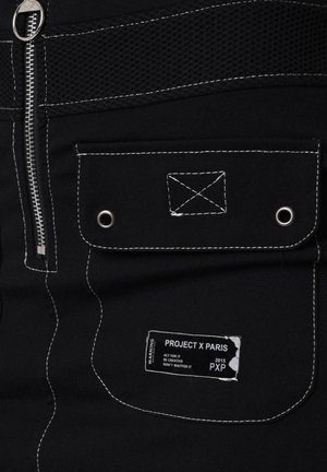 Shorts neri in tessuto, dotati di chiusura con zip, pannello in rete, cuciture bianche a contrasto e etichetta con "PROJECT X PARIS" e istruzioni per la cura.