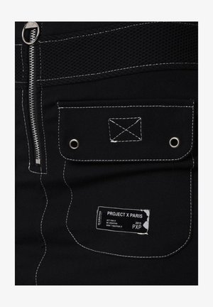 Shorts neri in tessuto, dotati di chiusura con zip, pannello in rete, cuciture bianche a contrasto e etichetta con "PROJECT X PARIS" e istruzioni per la cura.