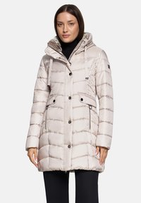 Manteau matelassé beige clair avec une capuche à motif, une fermeture éclair frontale et des accents à boutons. Le matériau est brillant avec un design matelassé.