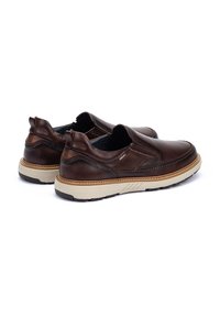 Zapatos slip-on de cuero marrón con un acabado texturizado, suela beige en contraste y un sutil detalle de costura para un diseño añadido.