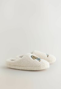Vita fleece tofflor med en mjuk textur, med blå och guld broderade detaljer på ovansidan. Rundad tå och öppen baksida.