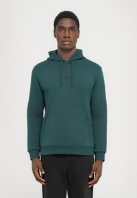 Felpa con cappuccio verde scuro realizzata in tessuto morbido, con tasca frontale, cappuccio regolabile con coulisse e logo discreto sul petto.