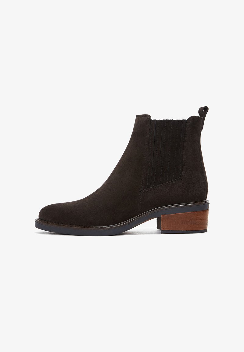 Botte cheville en daim marron avec un bout rond, des panneaux latéraux élastiques et un talon carré avec une accent en bois. Texture douce et design minimal.