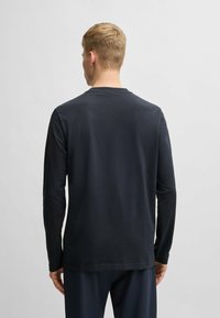 Long-sleeve t-shirt in dark navy cotton with a crew neckline and relaxed fit. Smooth texture, minimalistic design, no visible graphics or patterns.