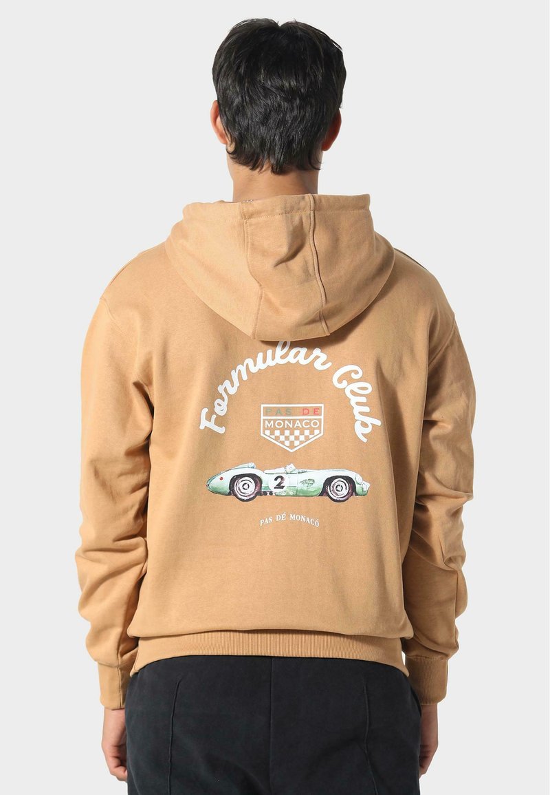 Sudadera con capucha marrón que presenta un gráfico de un coche de carreras y el texto "Formula Club" en la parte posterior. Fabricada con un tejido suave y con un corte relajado.