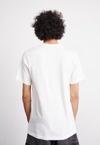 Tricou alb cu maneci scurte, cu decolteu la baza gatului, fabricat din bumbac. Textură netedă, croială dreaptă, fără logo-uri sau modele vizibile.