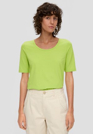 Limoengroene t-shirt met korte mouwen en een ronde halslijn, gemaakt van zachte stof, gecombineerd met beige broek met zijzakken en een knoopsluiting.