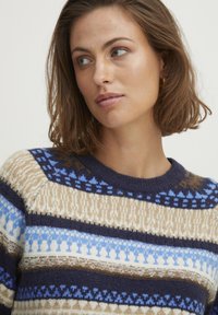 Strikket sweater med rund halsudskæring, der har vandrette striber i creme, blå og brun. Strukturerede mønstre i strikkedesignet.