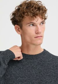 Mørk grå strikkegenser med rund hals og ribbede mansjetter, med et strukturert mønster. Stoffet ser mykt og varmt ut.