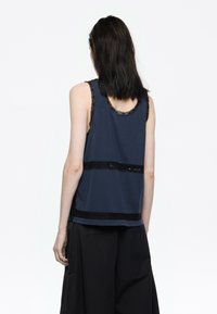 Canottiera blu navy con bordo in pizzo al collo e all'orlo, caratterizzata da accenti in pizzo nero a contrasto e una vestibilità rilassata.