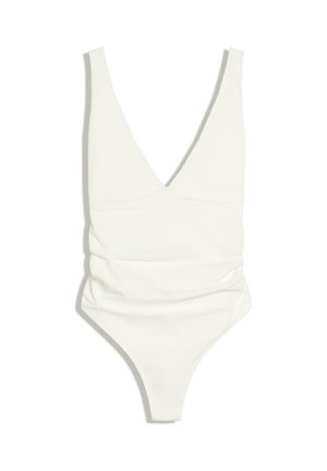 Maillot de bain une pièce blanc avec décolleté en V profond, larges bretelles et détails froncés à la taille, posé à plat sur un fond blanc.