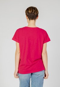 Maglietta rosa a maniche corte realizzata in tessuto morbido, con una vestibilità comoda e un neckline arrotondato. Il retro è privo di grafiche o decorazioni.