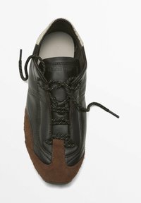 Brown suede and black leather sneaker with round toe, contrasting textured accents, and dark laces. Brand logo inside the shoe.