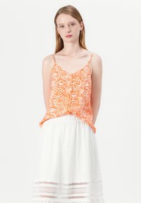 Top fără mâneci, cu model portocaliu, cu bretele subțiri, asortat cu o fustă albă din dantelă, având broderie texturată și un accent din dantelă.
