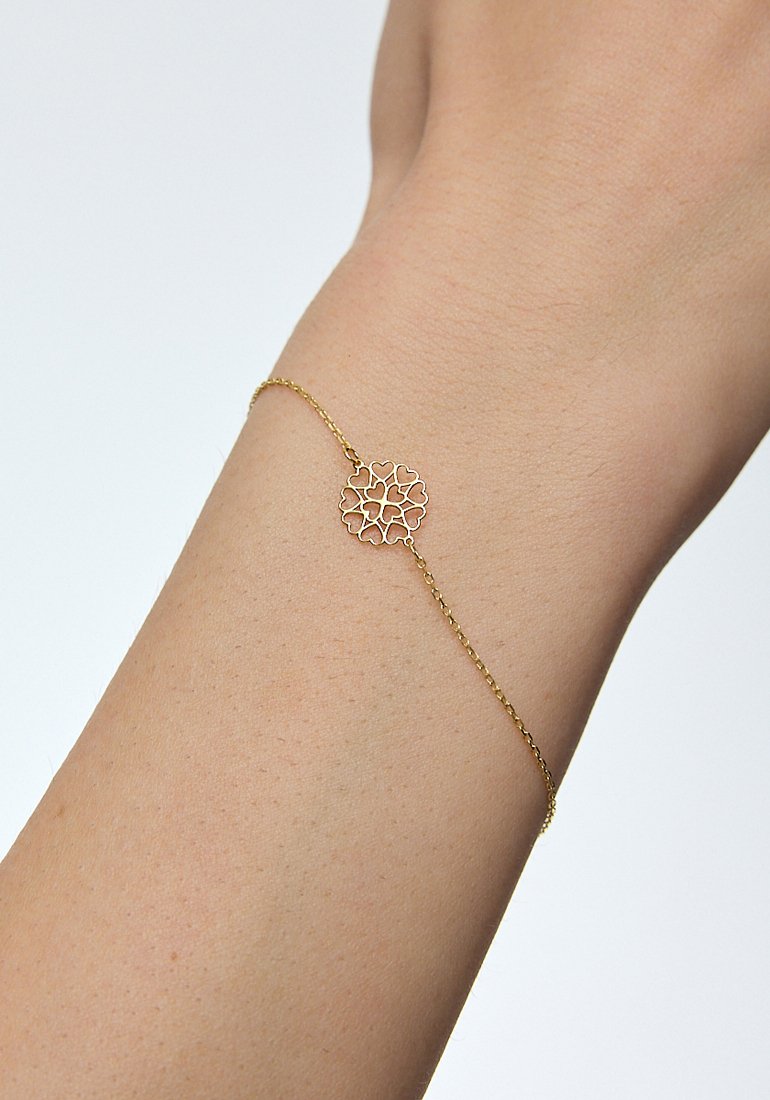 Złota bransoletka z delikatnym łańcuszkiem i okrągłym, misternie wykonanym centrum w kwiatowym wzorze z ażurowymi motywami.