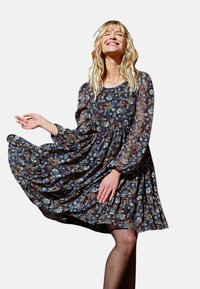 Abito a fiori con maniche lunghe, collo rotondo e vita arricciata. Sfondo scuro con fiori multicolori, gonna fluida e texture trasparente.