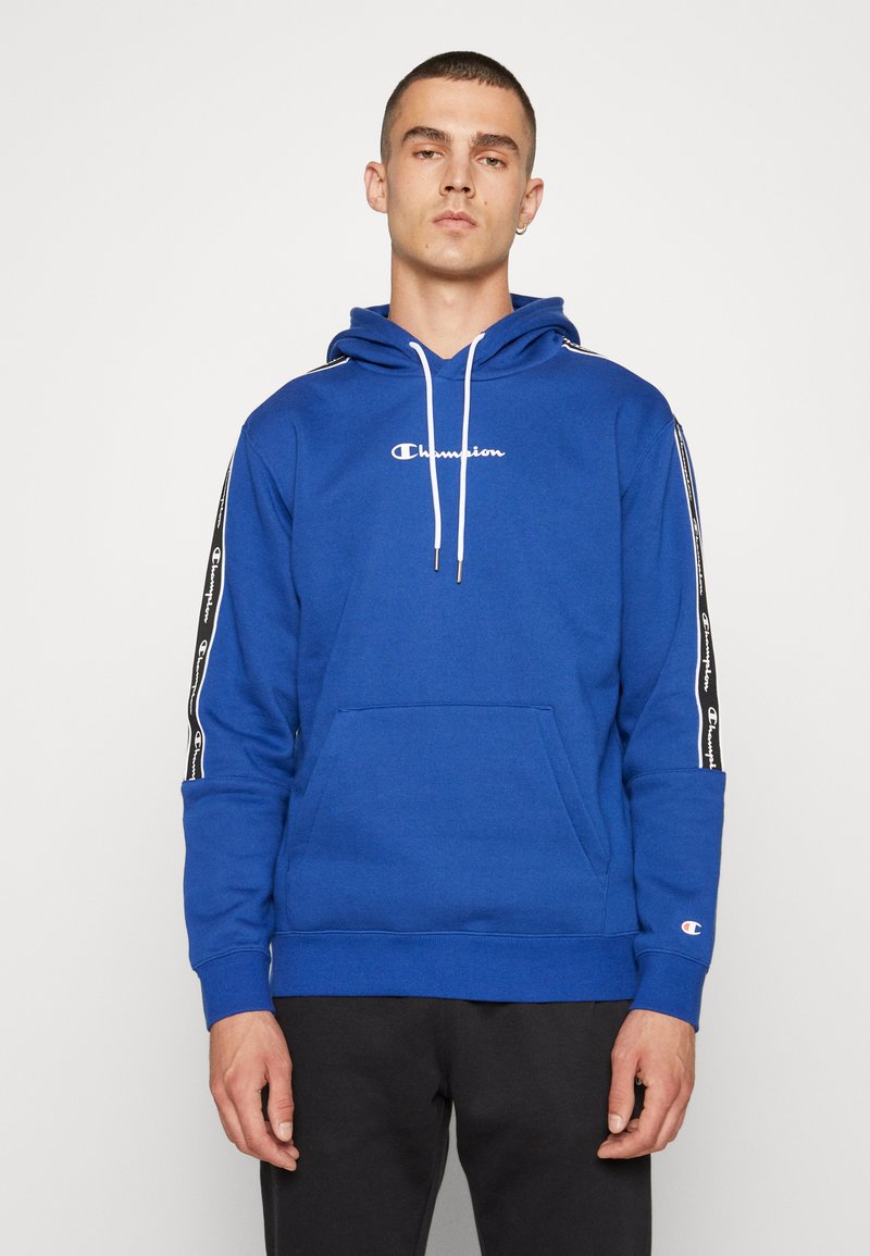 Felpa in cotone blu con tasca frontale, coulisse bianca e logo. Presenta strisce nere sui lati con motivo a logo ripetuto. Polsini a costine.