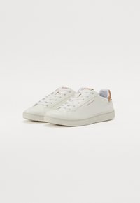 Hvit lær sneakers med en jevn tekstur, flate gummisåler, rund tå og lys brun hælaccent. Har snøring og logodetalj.