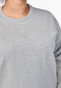 Gray sweatshirt made of soft fabric, featuring a round neckline and slightly textured surface. Includes a subtle embroidered logo on chest.