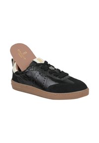 Sneaker nera con un design di materiali misti, accenti in pelle lucida e suede, suola in gomma marrone e perforazioni decorative.