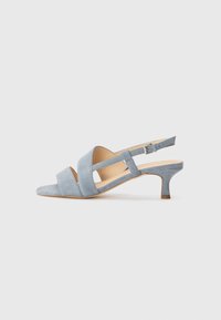 Light blue suede slingback shoes with a low heel, featuring crisscross straps and an open toe design. Smooth texture and minimal hardware.
