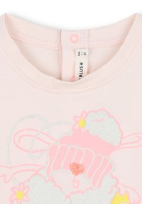 T-shirt in cotone rosa chiaro con una grafica in glitter argento di una pecora con un cappello rosa e decorazioni floreali, completo di chiusura a scatto sul collo.