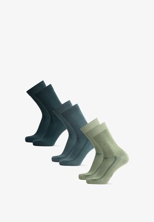 Vier Paar Socken in verschiedenen Grüntönen und Blautönen. Das Material sieht weich aus, mit einer glatten Textur und gerippten Bündchen. Auffällige Nahtdetails.