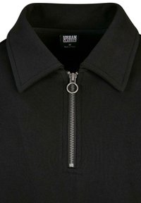 Svart zip-up polo skjorta med platt krage, försedd med en metalldragkedja och textilstruktur. Urban Classics-märket syns inne i kragen.