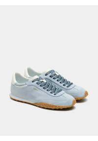 Zapatillas deportivas de gamuza azul claro con suela de goma texturizada, detalles en blanco contrastante y cordones azul oscuro, con un logo cosido.