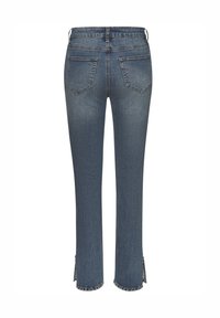 Tumši zili džinsi ar pieguļošu griezumu, kas aprīkoti ar divām aizmugurējām kabatām un šķirtām apakšmalām, rotātām ar kniedēm. Klasiska šuvju detaļa visā apģērbā.