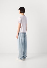 Kort lavendel T-skjorte med avslappet passform, kombinert med løse lyseblå jeans. Antrekket har en jevn tekstur og et enkelt design.