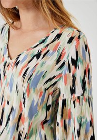 Blusa con escote en V, patrón abstracto multicolor en verde, coral, negro y beige; tela ligera con un corte relajado.